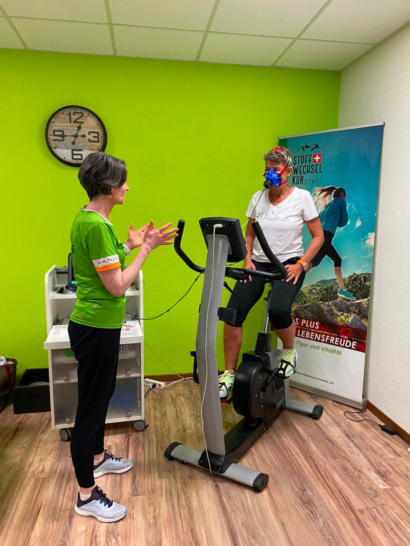 Spiroergometrie im Diagnostikcenter Othmarsingen: Sportlerin mit Atemmaske auf dem Fahrradergometer, Coach begleitet den Test